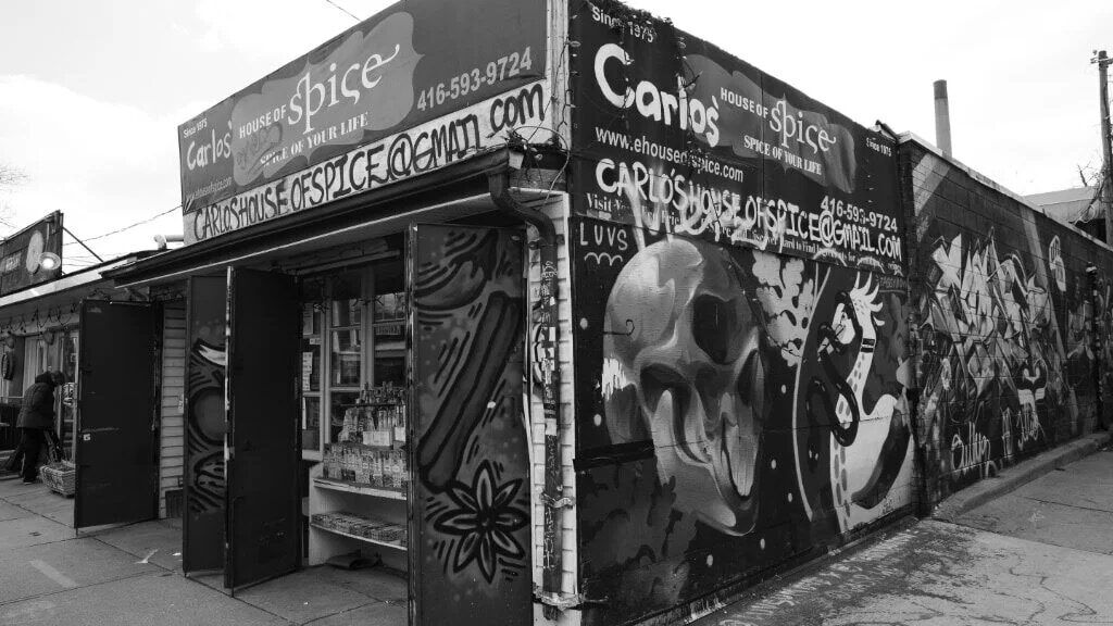 The graffiti-covered corner of Carlos' House of Spice on Augusta Ave, photographed in black and white